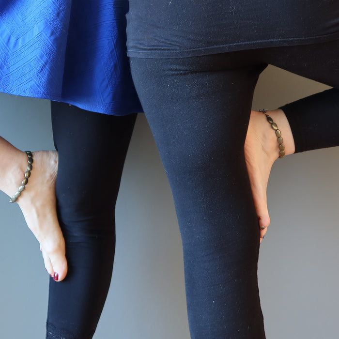 two women with feet on thigh yoga pose wearing pyrite anklets