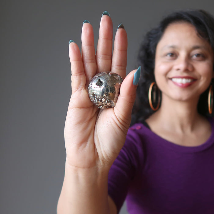 sheila from satin crystals with a gold pyrite geode sphere in her palm
