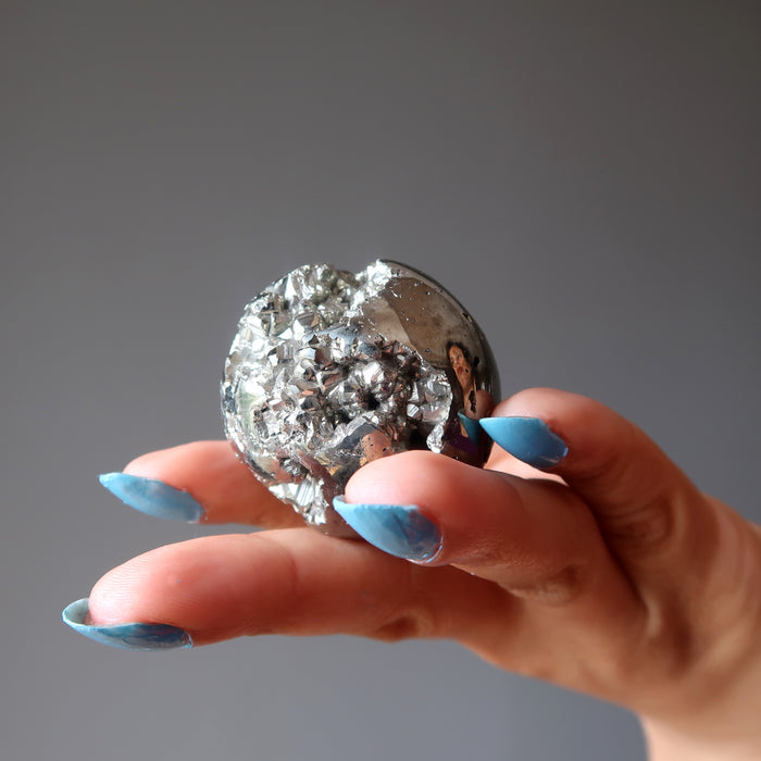 hand holding gold pyrite geode sphere