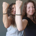 two women flex their biceps while showing off their gold pyrite faceted bracelets
