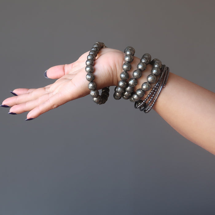 5 Pyrite bracelets stacked up on a lady's wrist