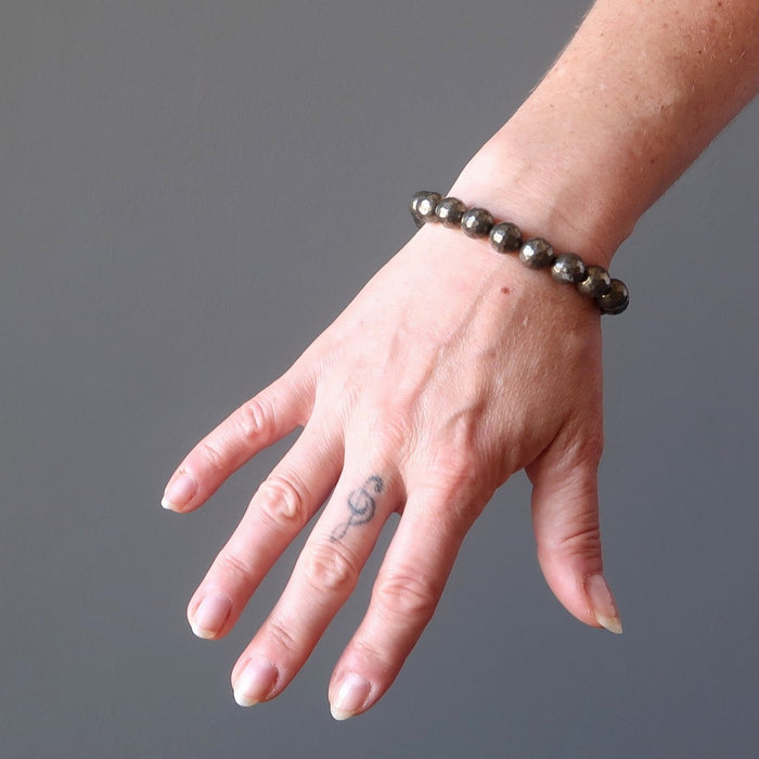 a round beaded gold pyrite bracelet on a model's wrist