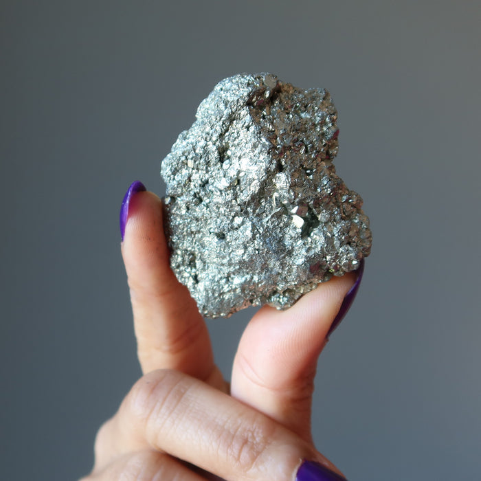hand holding raw pyrite cluster