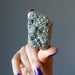 hand holding raw pyrite cluster'