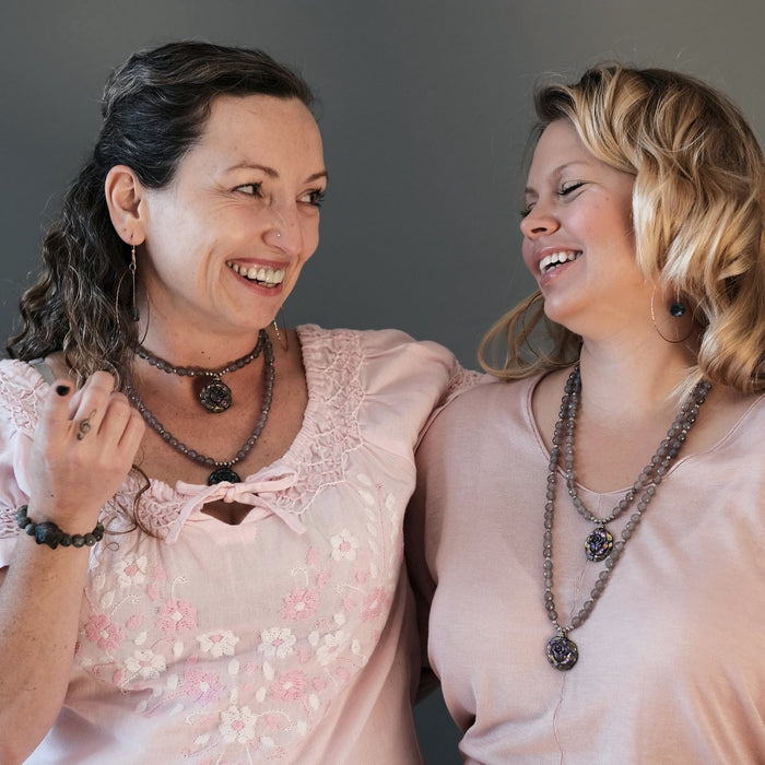 two friends laughing together wearing matching pyrite rose necklaces