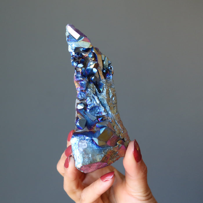 hand holding raw rainbow aura titanium quartz cluster