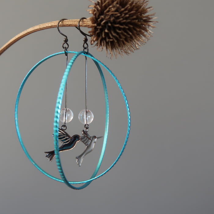 quartz hummingbird hoop earrings hanging on a branch