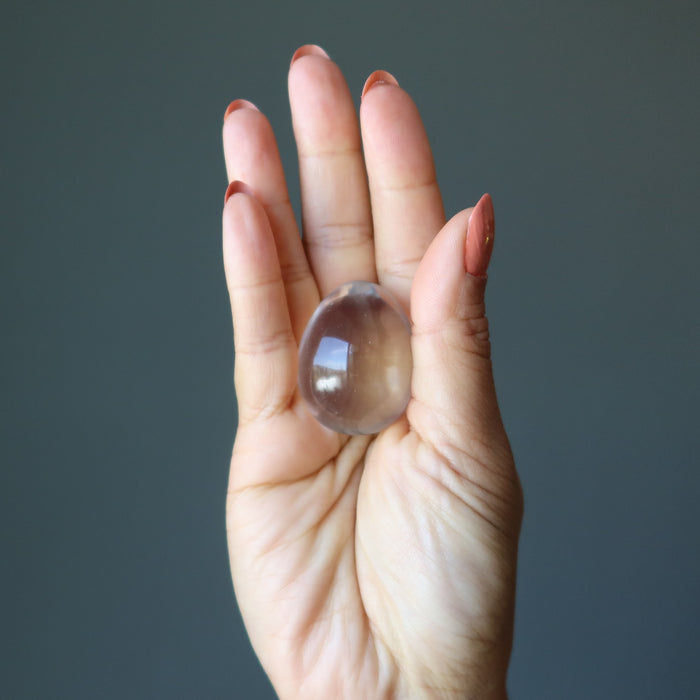 hand holding clear quartz crystal egg
