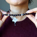 sheila of satin crystals lifting lower part of a clear quartz merkaba pendant on beaded faceted brown chalcedony necklace from her neck