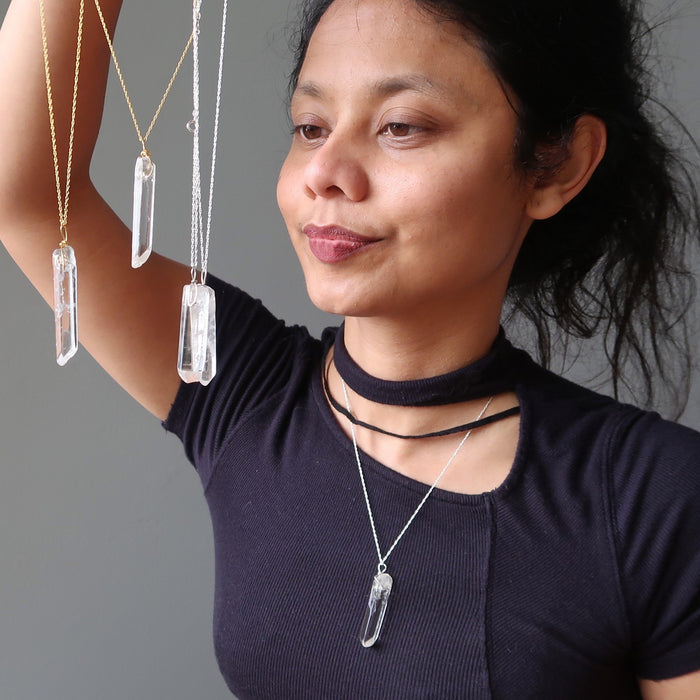 sheila of satin crystals gazing at 4 raw clear quartz necklaces and wearing one