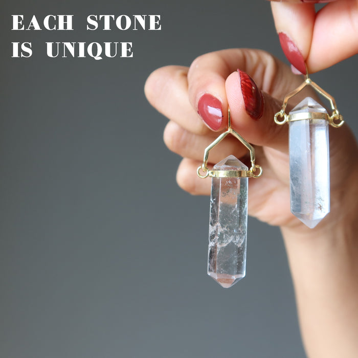 hand holding clear quartz double terminated pendants to show difference