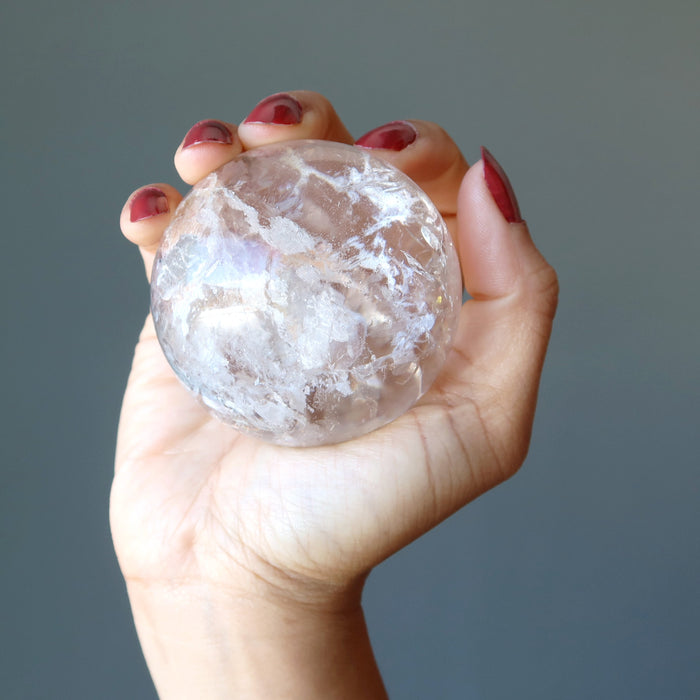 hand holding clear quartz sphere