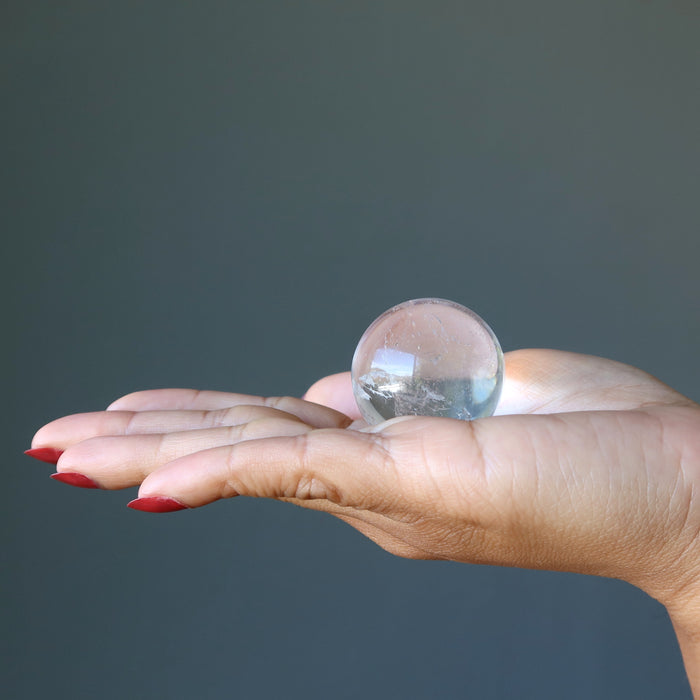 hand holding clear quartz crystal ball