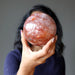 female model holding a red quartz sphere in front of her face