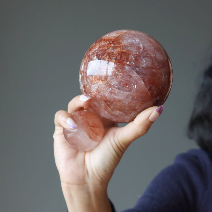 hand holding two red quartz spheres of different sizes