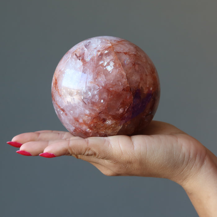 hand holding red fire quartz sphere 