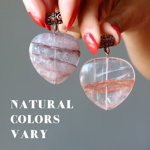 hands holding two fire quartz pendants to show natural colors vary