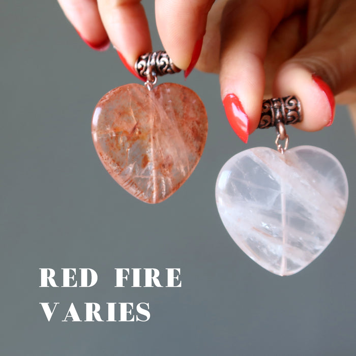 hands holding two fire quartz heart pendants