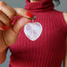 hand holding fire quartz heart pendant against chest