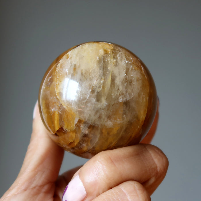hand holding a golden quartz sphere