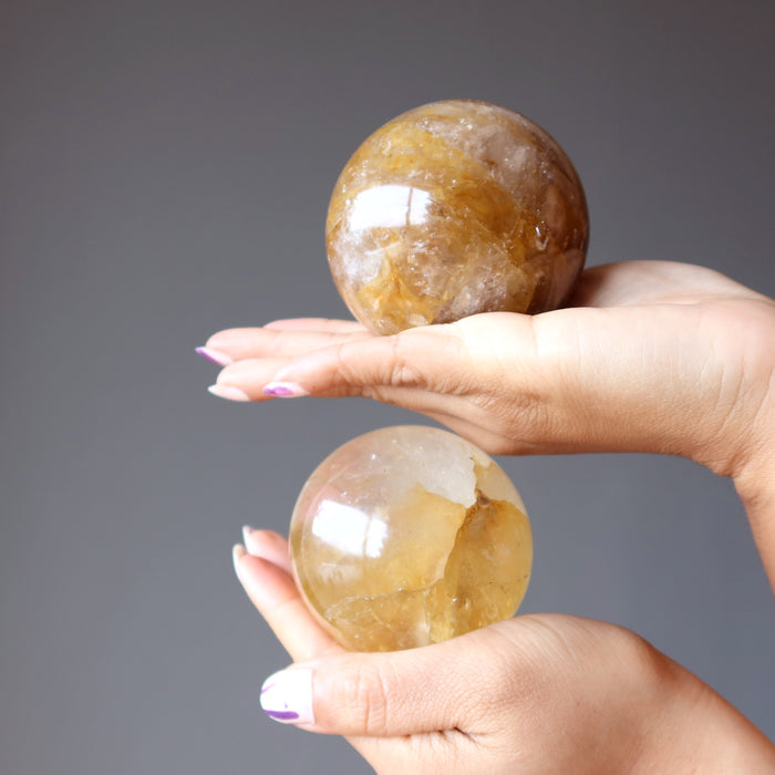 hands holding 2 golden quartz sphere