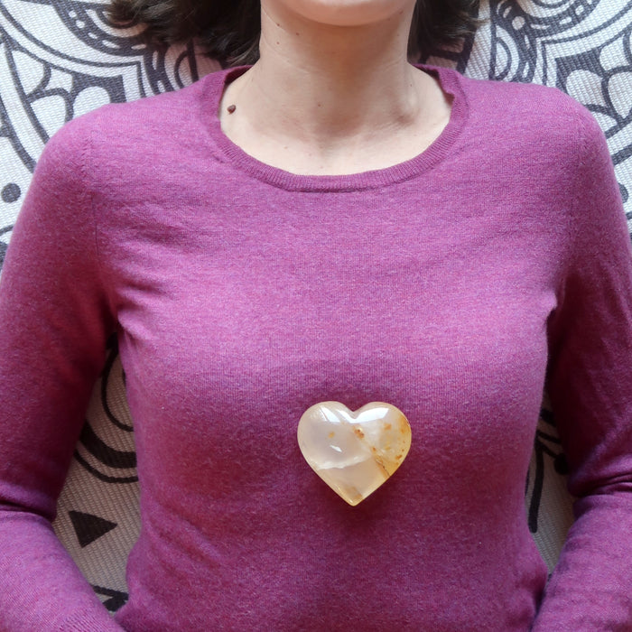 placing Golden Quartz Heart on female model chest