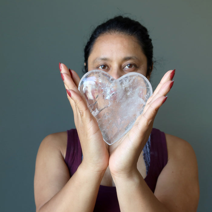 sheila of satin crystals holding a big Clear Quartz Heart with both hands in front of her face