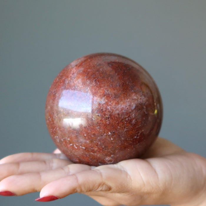 hand holding red hematite quartz sphere