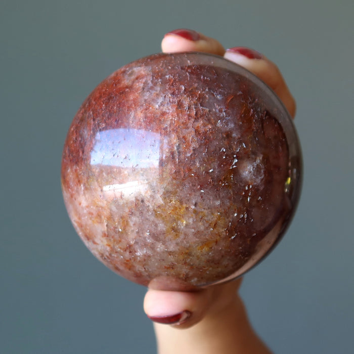 hand holding red hematite quartz sphere