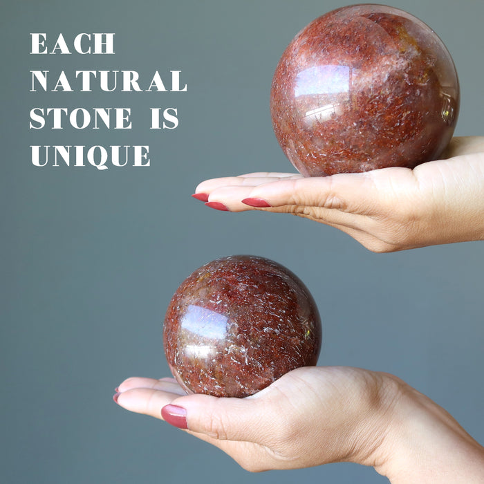 hands holding red hematite quartz spheres