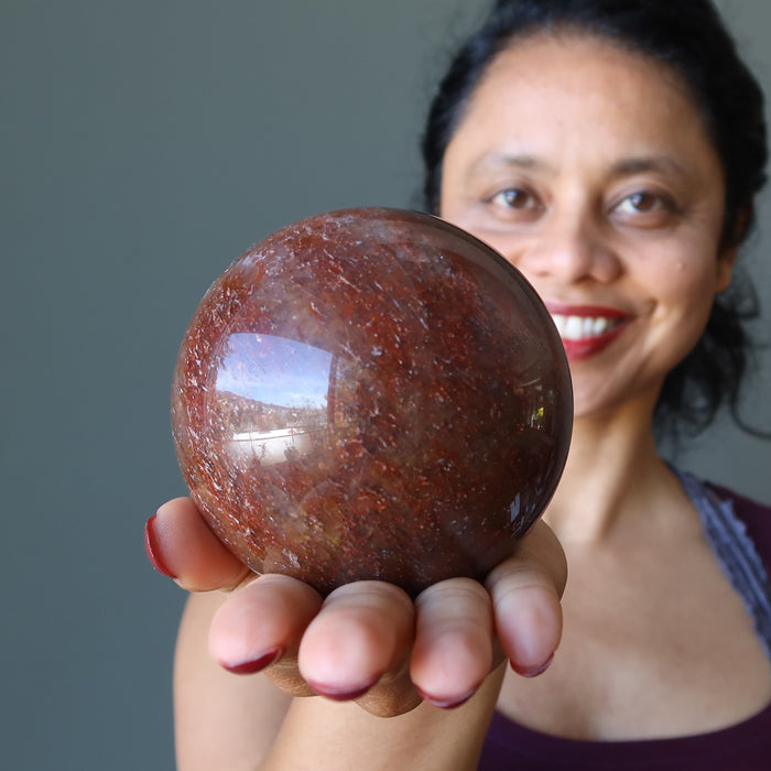woman  holding red hematite quartz sphere