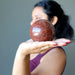 woman holding red hematite quartz sphere