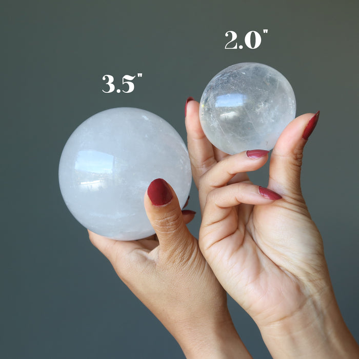 sheila of satin crystals holding two included quartz spheres to show size difference
