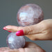 two hands holding lavender quartz spheres