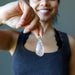 sheila of satin crystals holding a clear quartz with red fire inclusions in teardrop pendant 