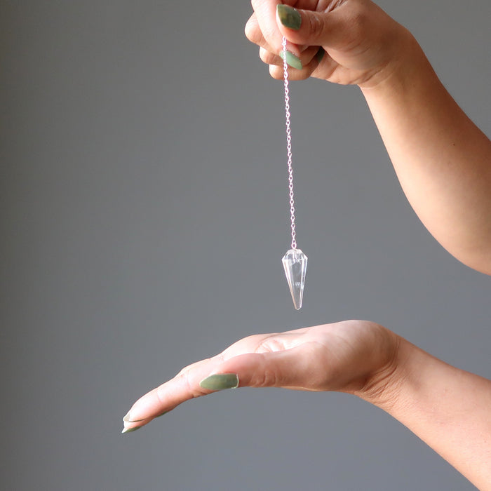 multi faceted clear quartz pendulum on sterling silver chain over hand