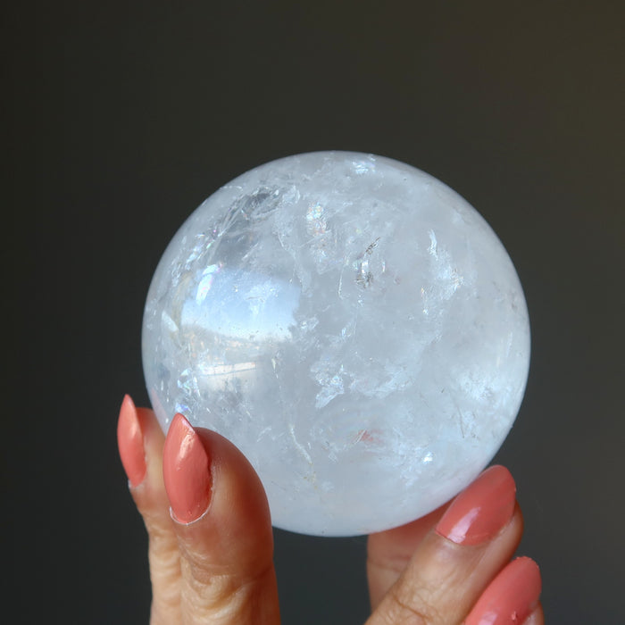 hand holding a clear quartz rainbow sphere