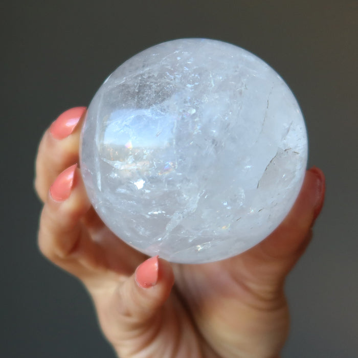 hand holding a clear quartz rainbow sphere