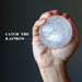hand holding a quartz sphere showing rainbow inclusions