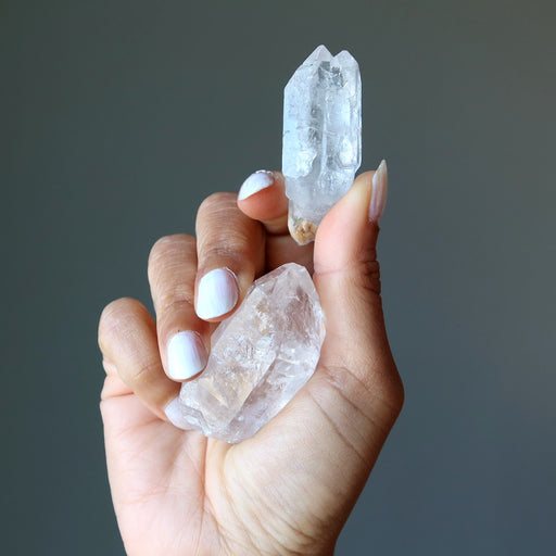 holding two raw clear quartz points