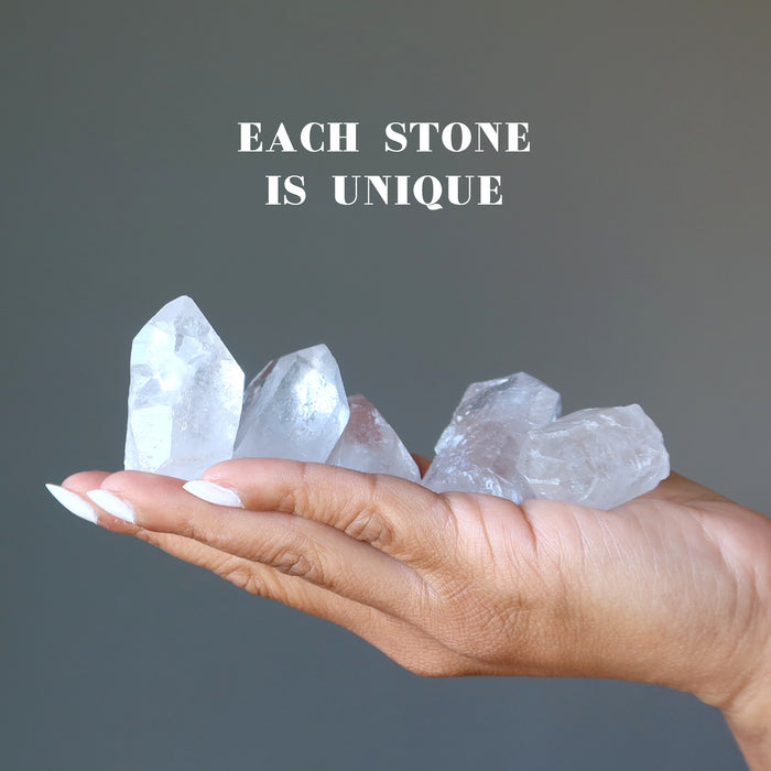 holding 5 raw clear quartz points on the palm each stone is unique