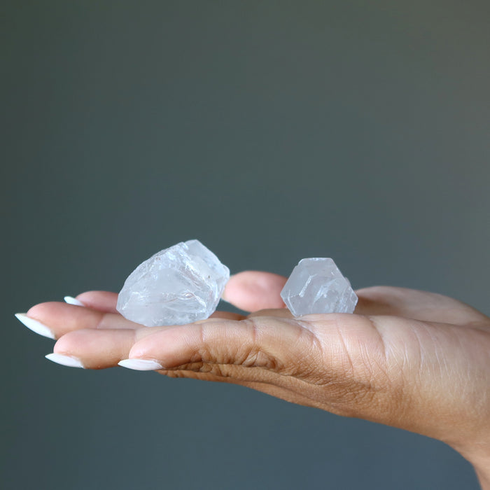 holding two raw clear quartz points on palm