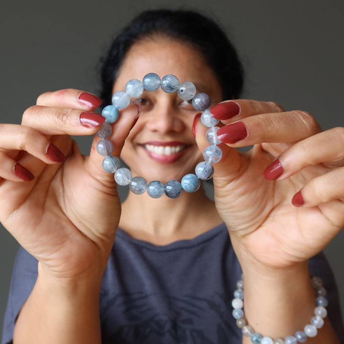 sheila of satin crystals holding and wearing rutilated blue quartz beaded stretch bracelet