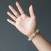 hand wearing a golden angel hair rutilated quartz stretch bracelet