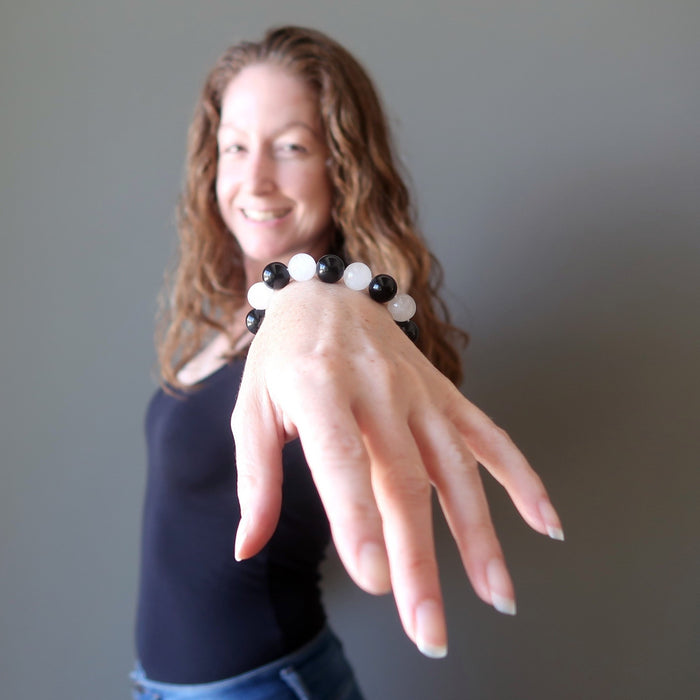 jamie of satin crystals with hand outstretched wearing white quartz and black obsidian round beaded stretch bracelet