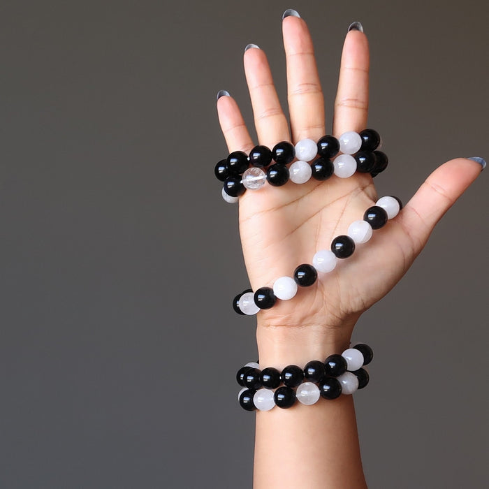 5 white quartz and black obsidian round beaded stretch bracelets on woman's hand