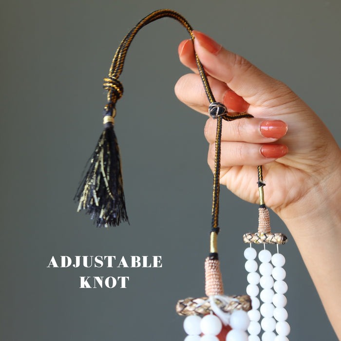 hand holding Snow white Quartz round beads strung in 3-strands of necklace on an adjustable tasseled clasp