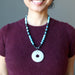sheila wearing sheila satin of satin crystals holding Jasper and apatite with Quartz donut medallion necklace