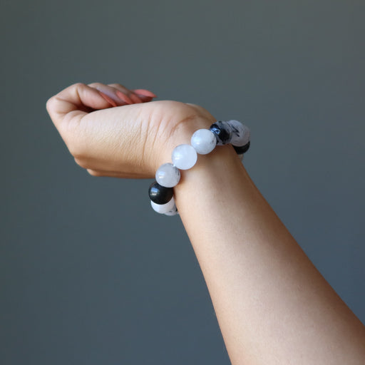 hand wearing black and white tourmalinated quartz beaded stretch bracelet