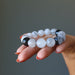 hand holding black and white tourmalinated quartz beaded stretch bracelet